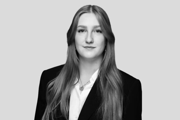 Eine junge Geschäftsfrau mit langen Haaren die in die Kamera lächelt.