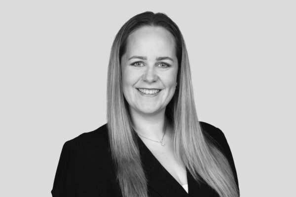 Eine Geschäftsfrau mit langen blonden Haaren die in die Kamera lächelt.